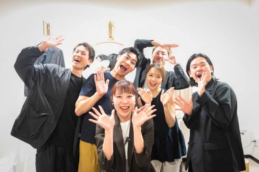 笑顔で手を振るSOLA KOBEのプランナーチーム